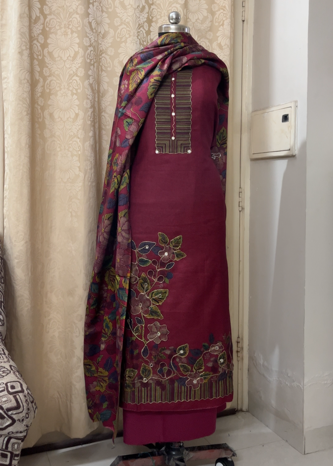 Maroon traditional outfit with floral patterns on a mannequin against a neutral background